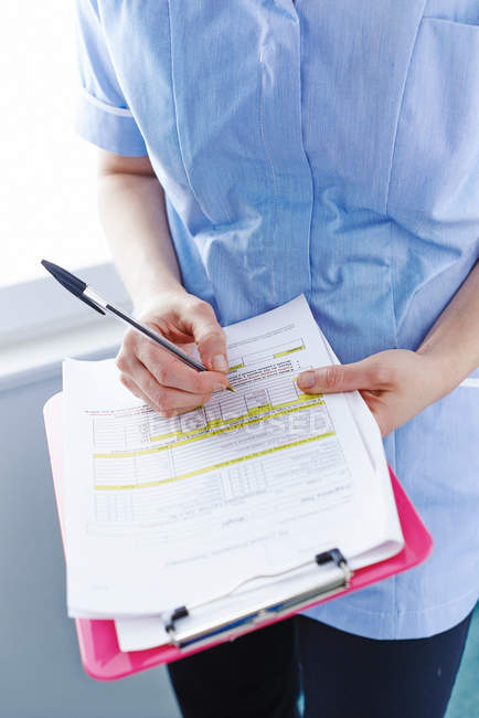 Mid-section of nurse writing paperwork — Stock Photo