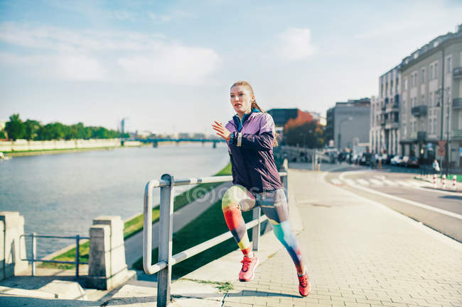 Середина доросла жінка біжить вздовж берега річки — стокове фото