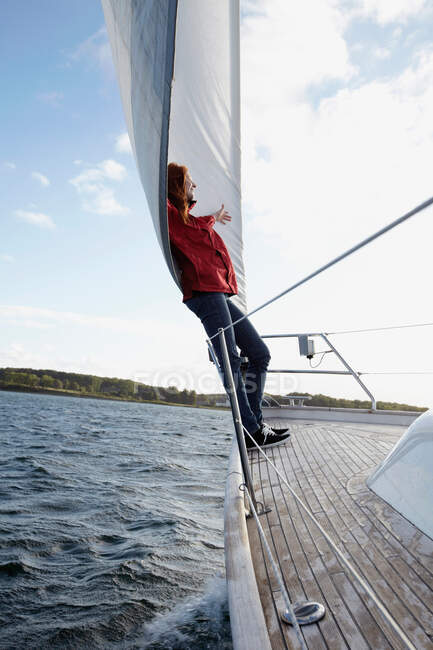 Woman leaning against sail on yacht — Stock Photo