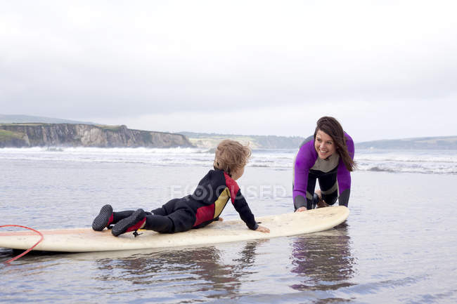 Mother teaching son how to surf — Stock Photo
