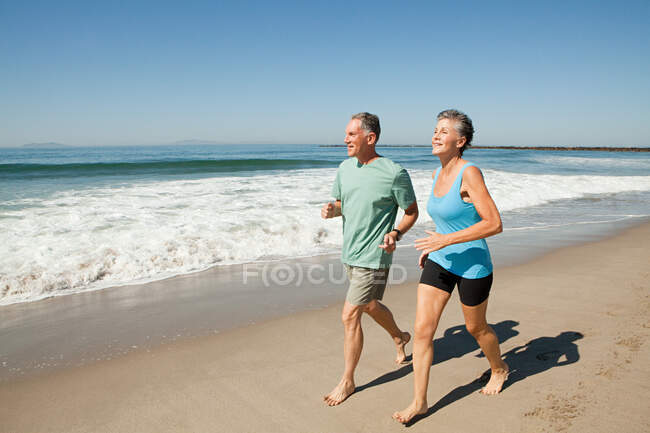 Couple aîné jogging sur la plage — Photo de stock