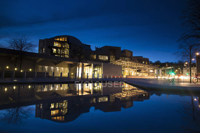 Observando a vista do edifício do Parlamento escocês refletida na água durante a noite — Fotografia de Stock