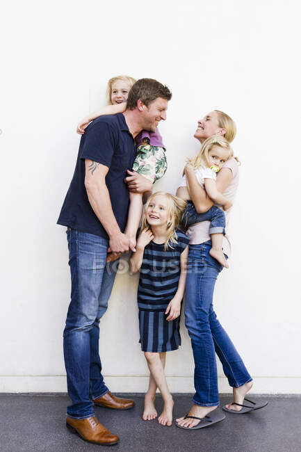 Retrato de pais e três filhas na frente da parede branca — Fotografia de Stock