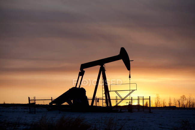 Силуэт нефтяной скважины на закате — стоковое фото