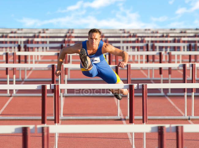 Male hurdler clearing hurdles — Stock Photo