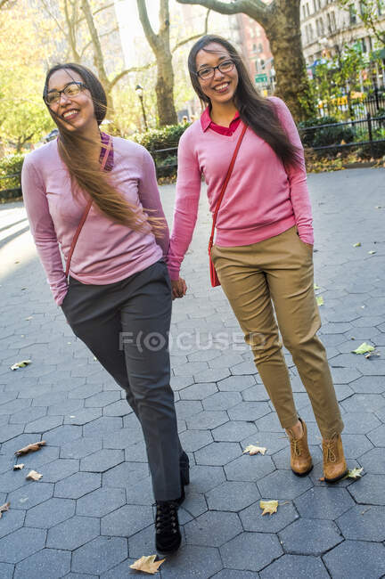 Сестры-близнецы держатся за руки, идут по улице — стоковое фото