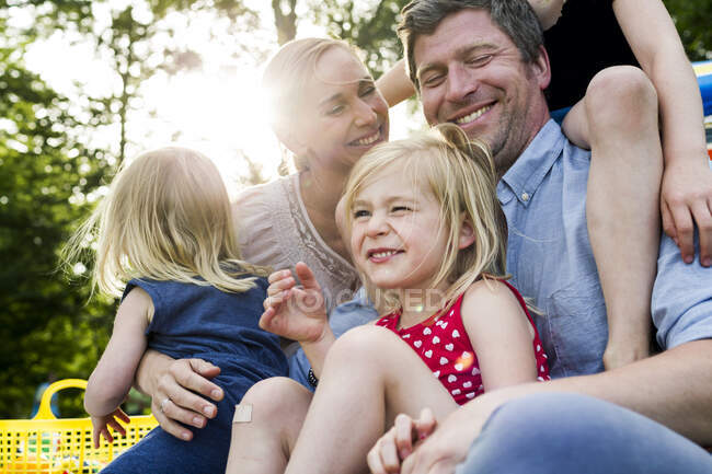 Padres felices y tres hijas compartiendo picnic familiar en el parque - foto de stock