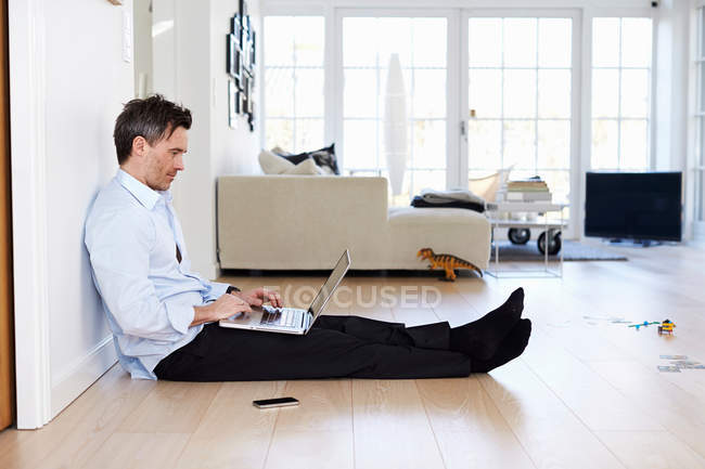 Uomo seduto sul pavimento e utilizzando il computer portatile — Foto stock