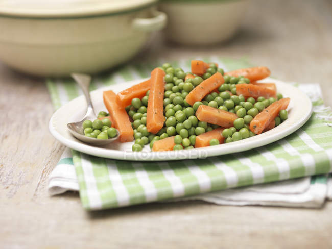 Plate of peas and carrots with mint and butter — Stock Photo