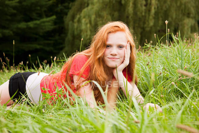 Teenage girl lying down on the grass chilling out — Stock Photo