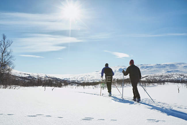 Due uomini che sciano nel campo innevato — Foto stock