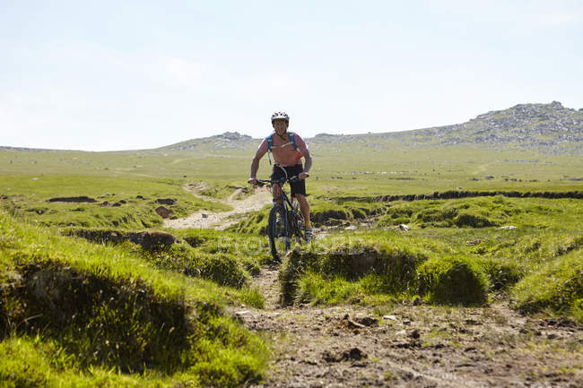 Cyclist cycling down hillside — Stock Photo