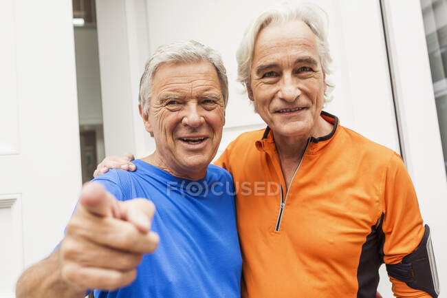 Portrait of two happy senior male runners at front door — Stock Photo