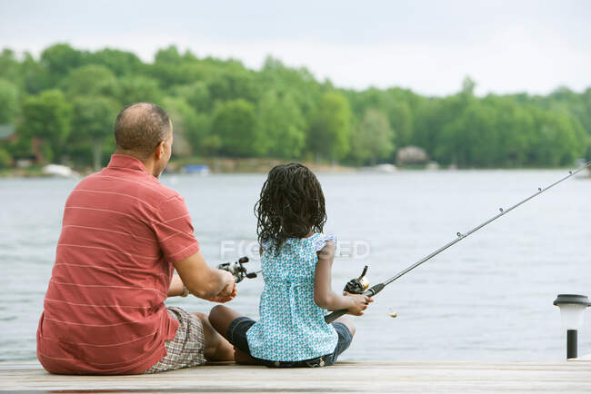Rear view of a grandfather and granddaughter fishing — Stock Photo