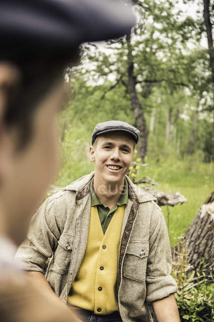 Young man wearing flat cap looking at friend smiling — Stock Photo