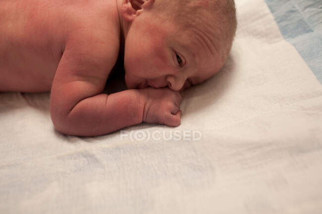 Menino recém-nascido deitado em sua frente — Fotografia de Stock