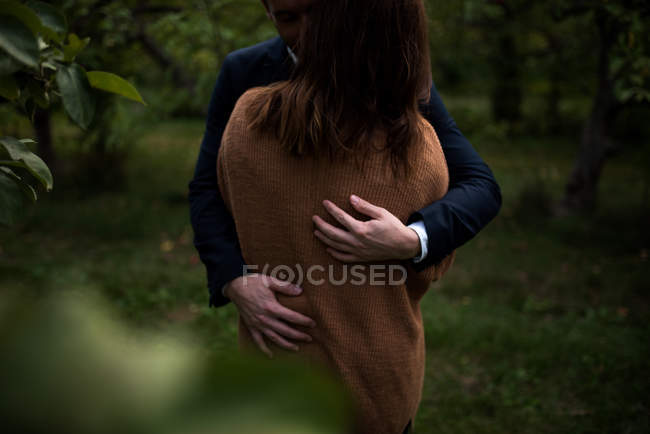 Casal romântico abraçando no pomar ao entardecer — Fotografia de Stock