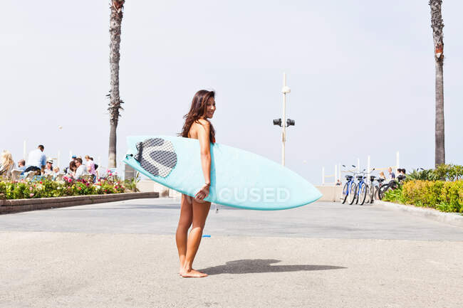 Mujer con tabla de surf, Hermosa Beach, California, EE.UU. - foto de stock