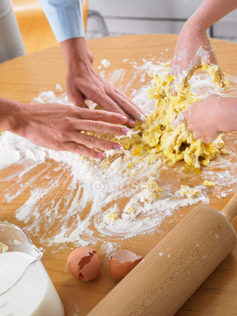 Cropped image of mother and daughter mixing ingredients for dough — Stock Photo