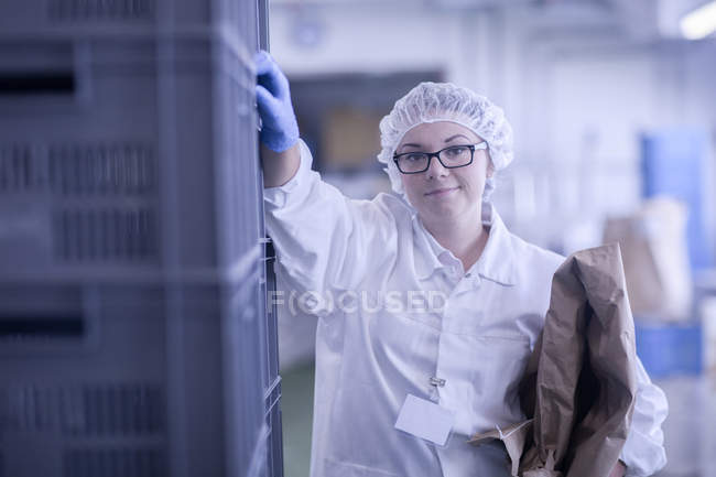 Trabalhador da fábrica segurando embalagem olhando para a câmera sorrindo — Fotografia de Stock