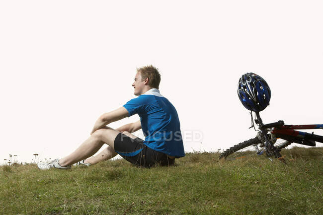 Um ciclista masculino descansando em um caminho de montanha — Fotografia de Stock