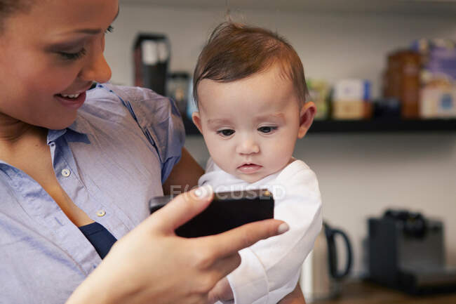 Mãe mostrando bebê menina smartphone — Fotografia de Stock