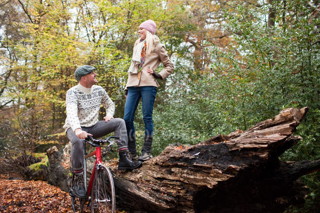 Uomo con bici e donna in piedi sul tronco — Foto stock