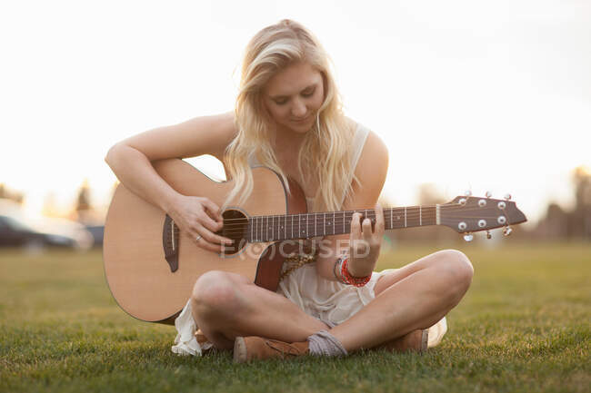 Woman playing guitar in grass — Stock Photo