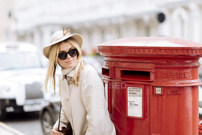 Stylische junge Frau wartet am roten Briefkasten, London, England, Großbritannien — Stockfoto