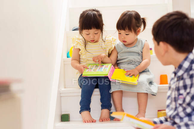 Female toddlers on stairs with game book — Stock Photo