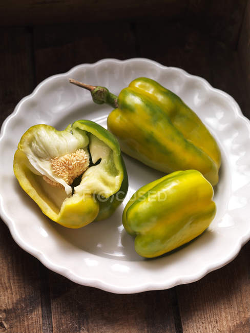 Green and yellow wholesome peppers and halved one in bowl — Stock Photo