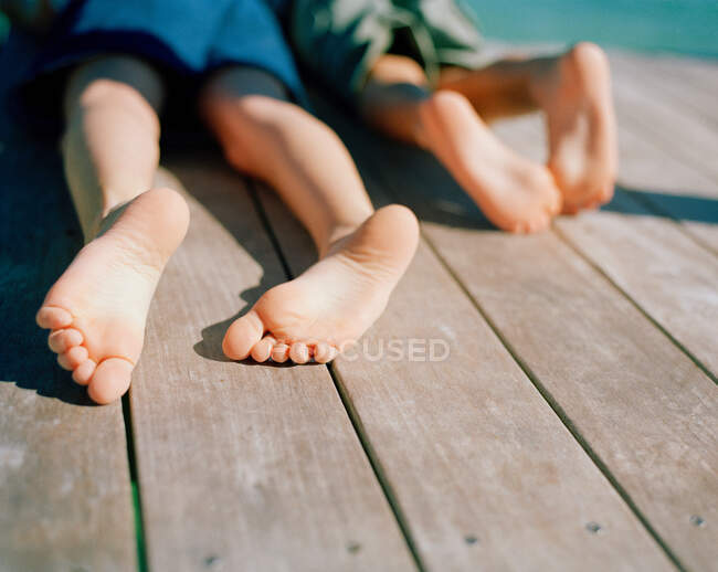 Due ragazzi sdraiati sul molo di legno, da vicino — Foto stock
