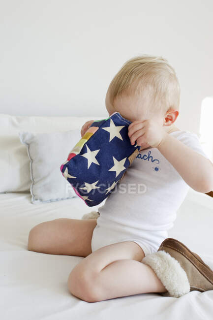 Female toddler peering into pencil case on bed — Stock Photo