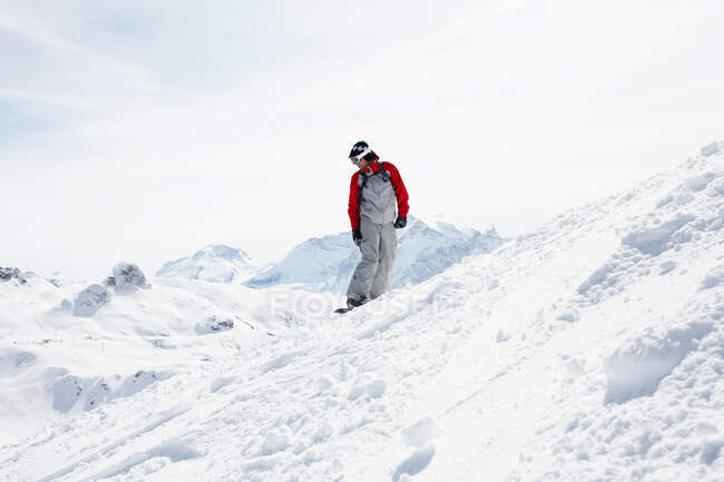 Person snowboarding on snow caped mountain descent — Stock Photo