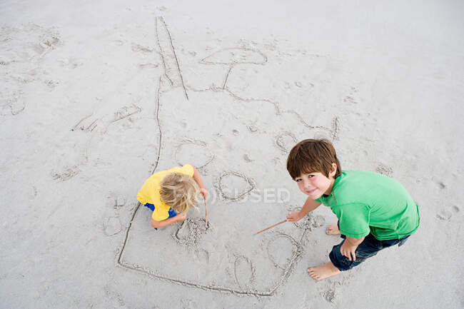 Мальчики рисуют на песке — стоковое фото