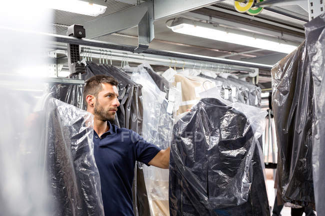 Hombre trabajador de almacén haciendo stock de prendas de vestir tomar en almacén de distribución - foto de stock