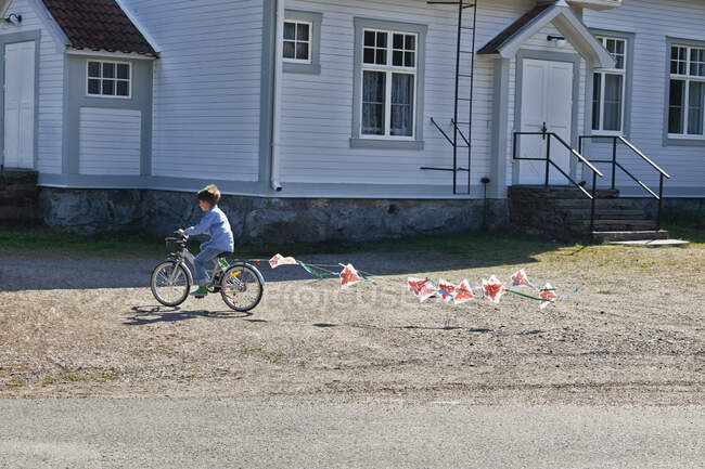Boy riding bicycle pulling bunting — Stock Photo