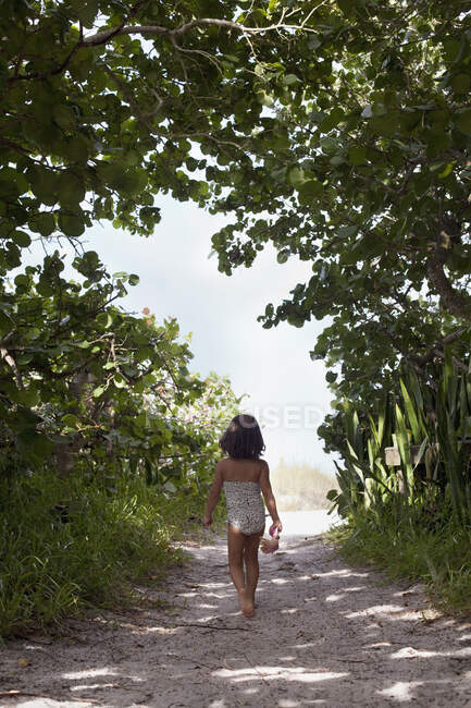 Дівчина в чорній сукні, що йде по пляжу — стокове фото