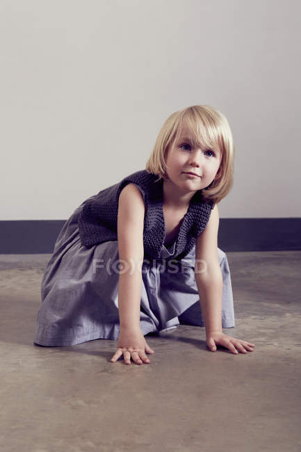 Mischievous girl crouching on floor — Stock Photo