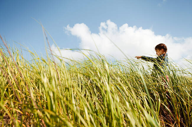 Menina apontando na grama longa — Fotografia de Stock