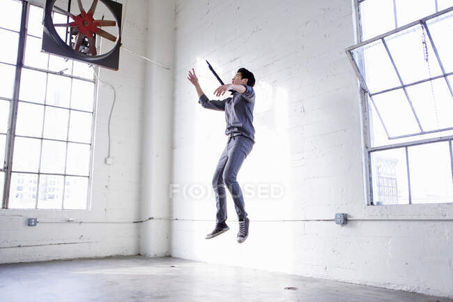 Jovem pulando em armazém vazio — Fotografia de Stock