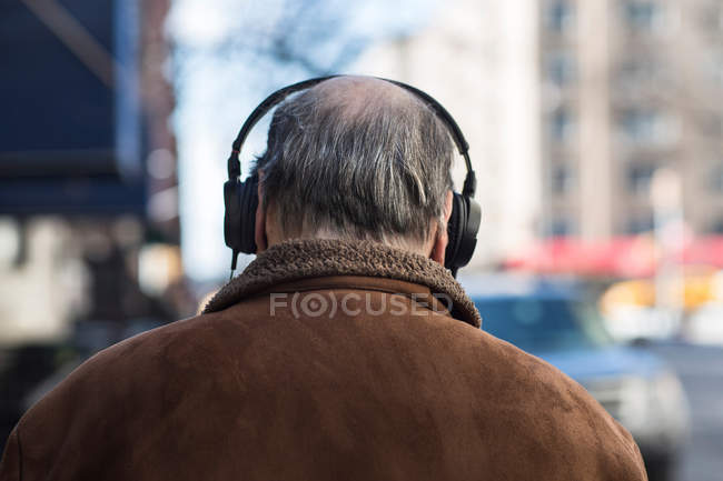 Вид сзади на пожилого человека в наушниках — стоковое фото