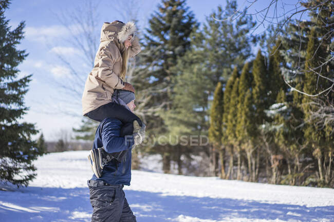 Mujer joven sobre hombros de hombre en la nieve, Montreal, Quebec, Canadá - foto de stock
