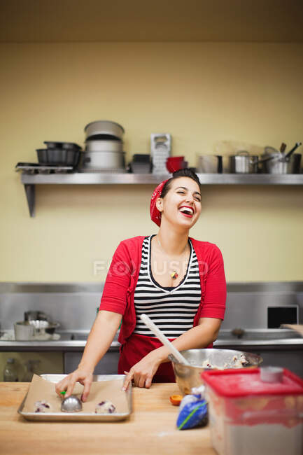 Jeune boulanger riant tout en préparant la nourriture — Photo de stock
