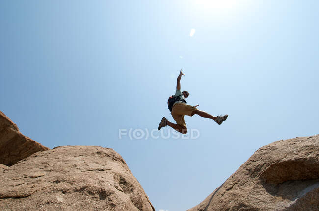 Человек прыгает между большими валунами — стоковое фото