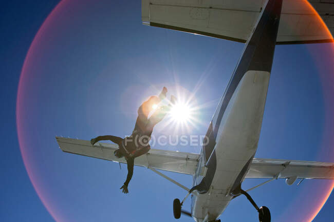 Parachutiste tombant de l'avion avec la lumière du soleil — Photo de stock