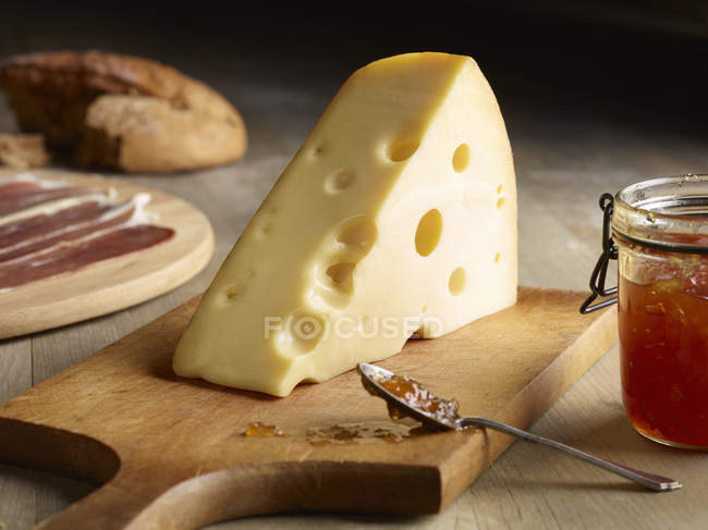 Natureza morta de queijo Edam com chutney de marmelo em tábua de corte — Fotografia de Stock