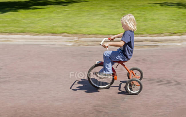 Side view of boy riding tricycle — Stock Photo