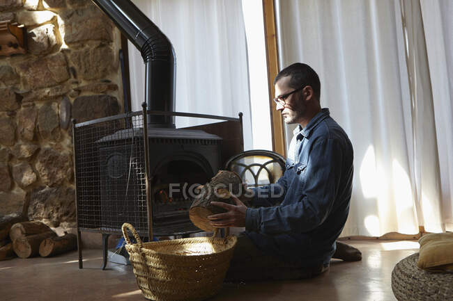Mid adult man preparing log fire — Stock Photo