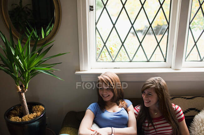 Two teenage girls sitting by window — Stock Photo